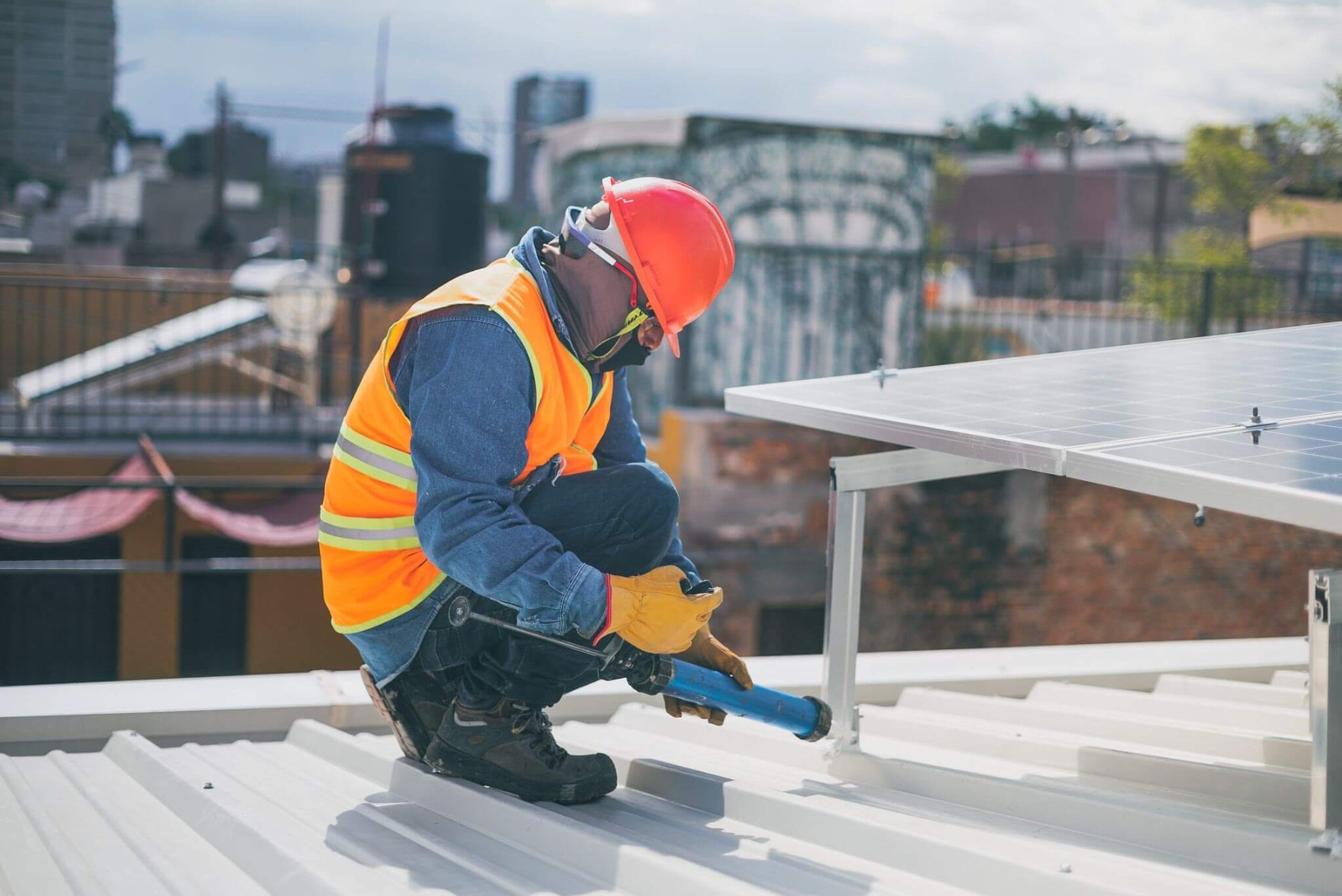 Construction worker installing solar panel on metal building roof