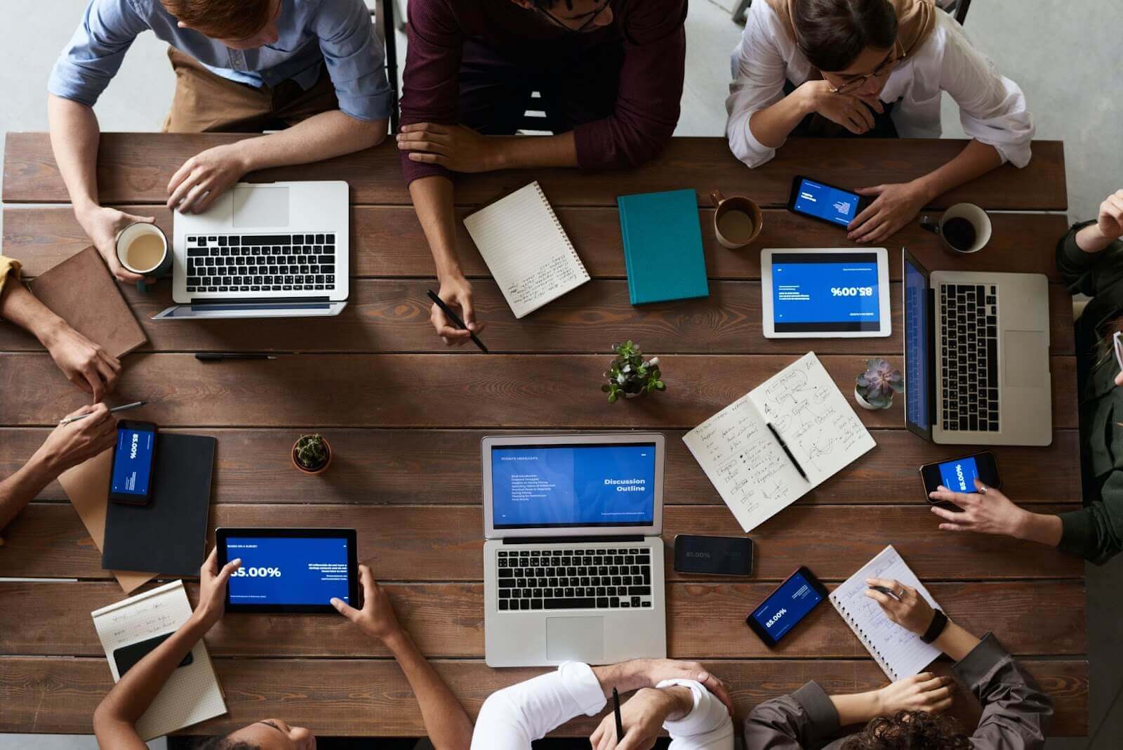 Group of coworkers sitting around a table with laptops and notebooks